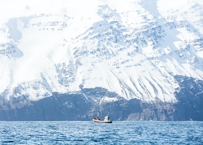 水面上的白色小船承载着积雪覆盖的山